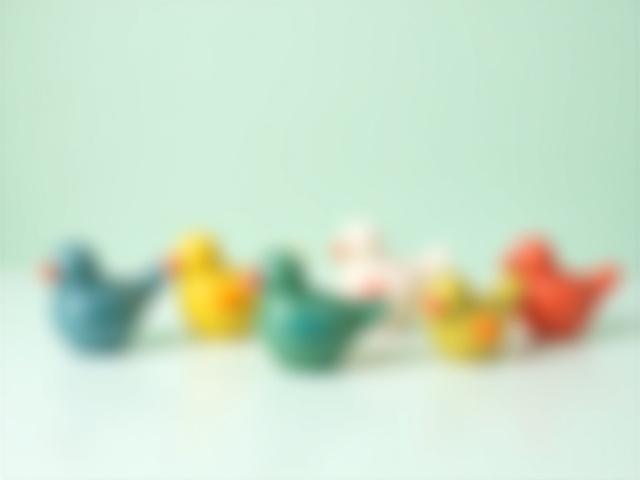 Eine Reihe kleiner, bunter Keramikvogelfiguren