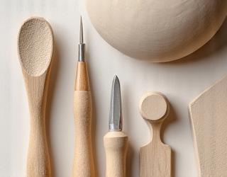 Verschiedene Töpferwerkzeuge und ein Klumpen Ton auf einer Werkbank